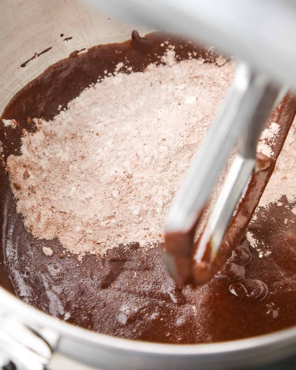 making pumpkin brownies - dry ingredient flour mixture added to the pumpkin brownie batter in a metal mixing bowl with the paddle attachment