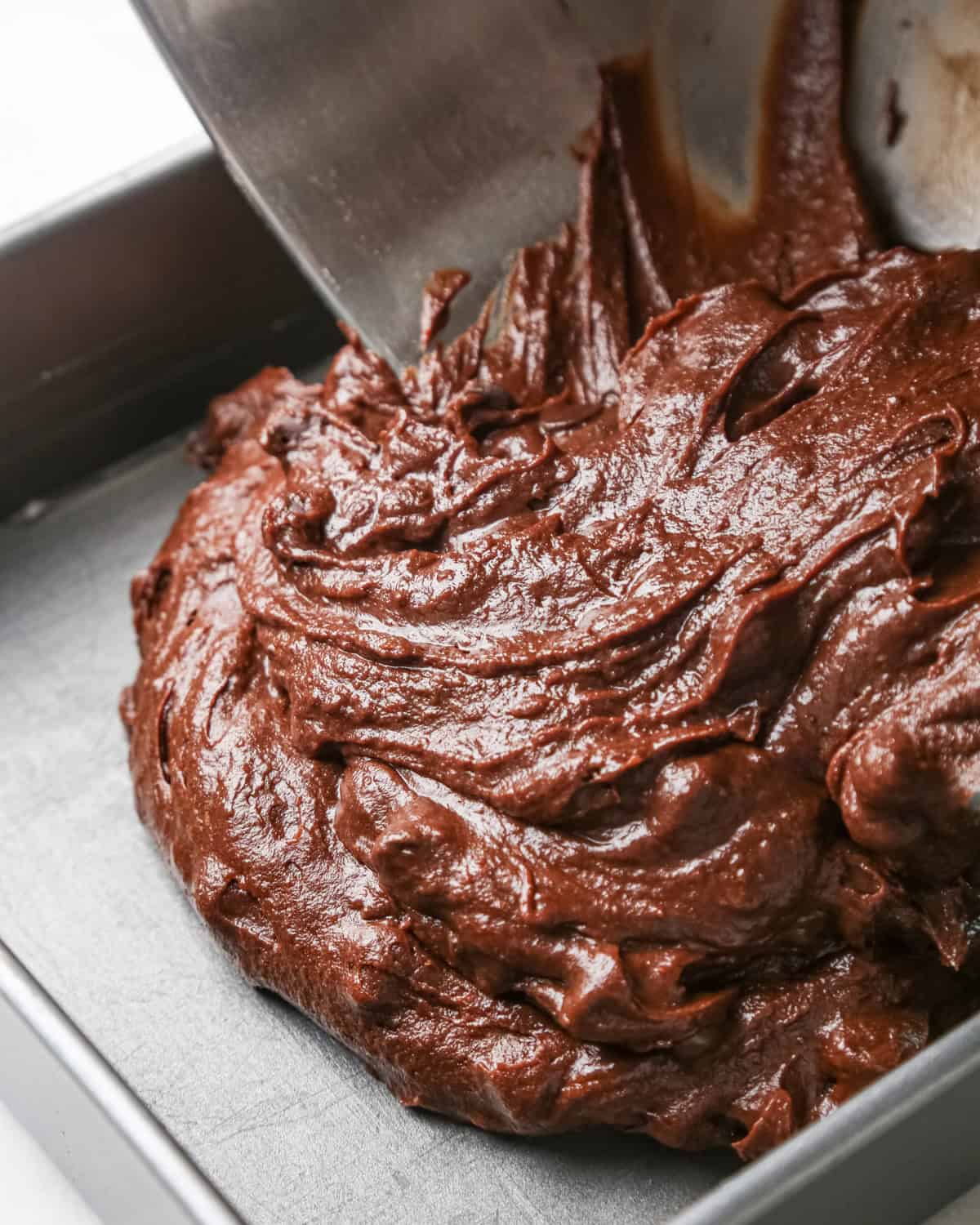 pumpkin brownies batter being poured into a metal baking dish