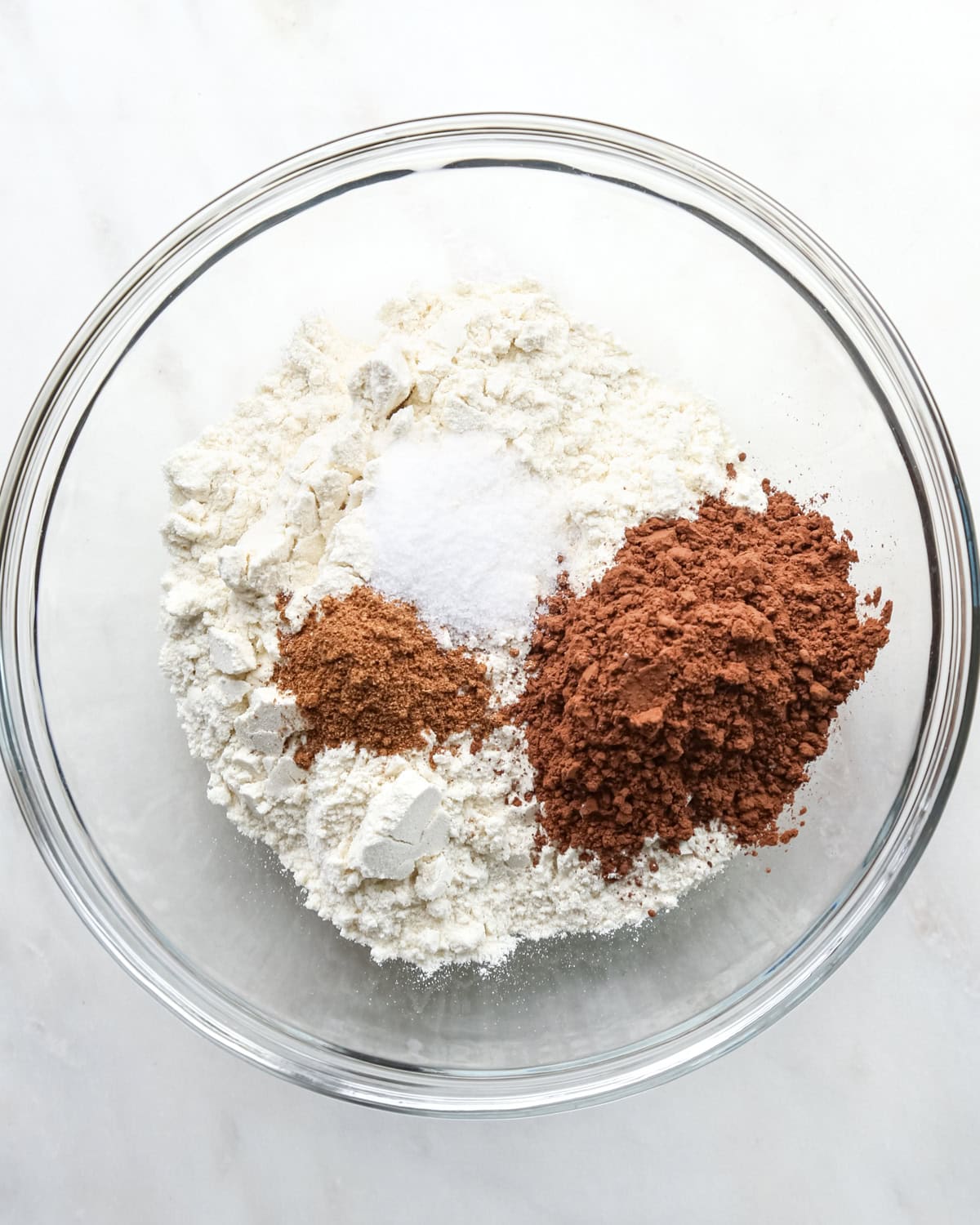 making pumpkin brownies - dry ingredients flour, salt, cocoa powder and pumpkin pie spice in a glass bowl before mixing