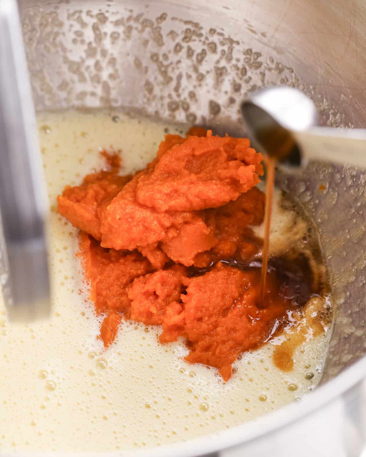 making pumpkin brownies - pumpkin and vanilla extract added to the beaten egg and sugar mixer in a metal mixing bowl