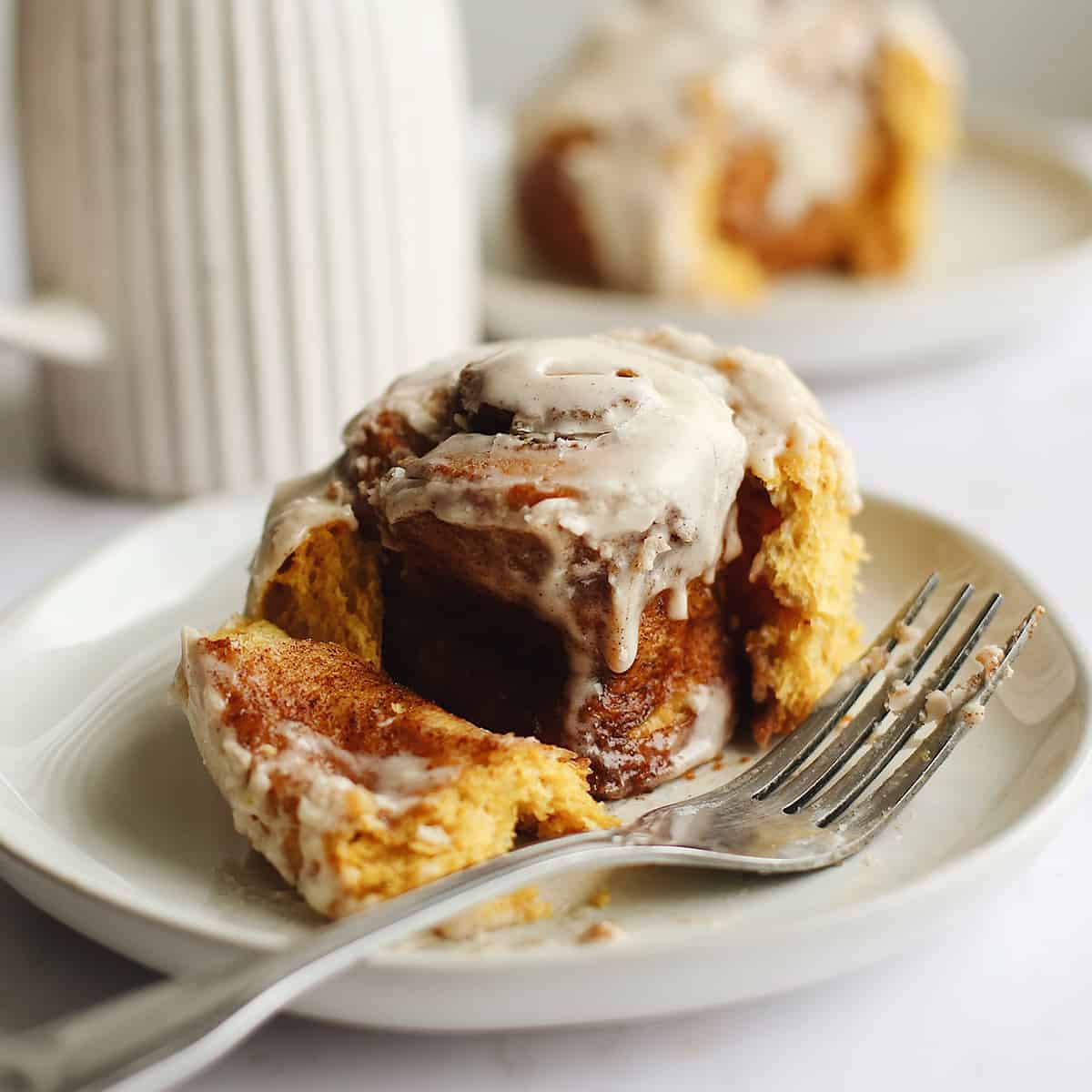 front view of a Pumpkin Cinnamon Roll on a plate with a fork