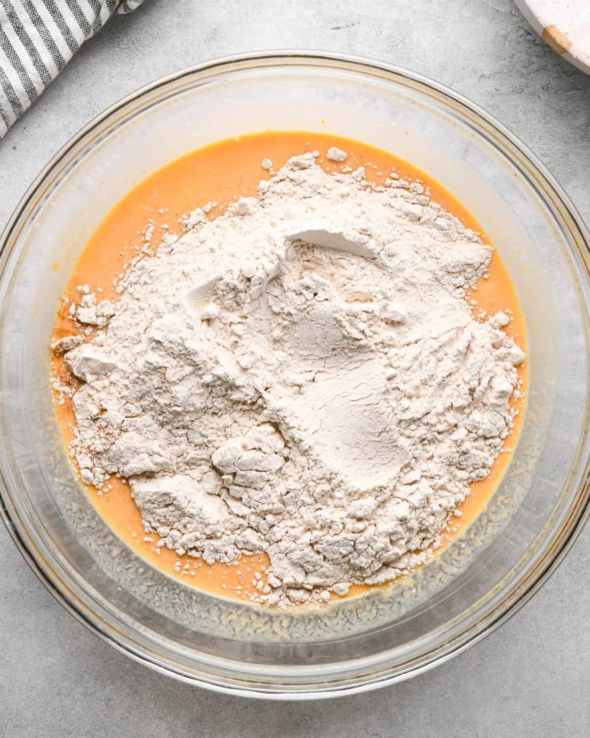 making pumpkin pancakes recipe - dry ingredients added to the wet ingredients before mixing in a glass bowl
