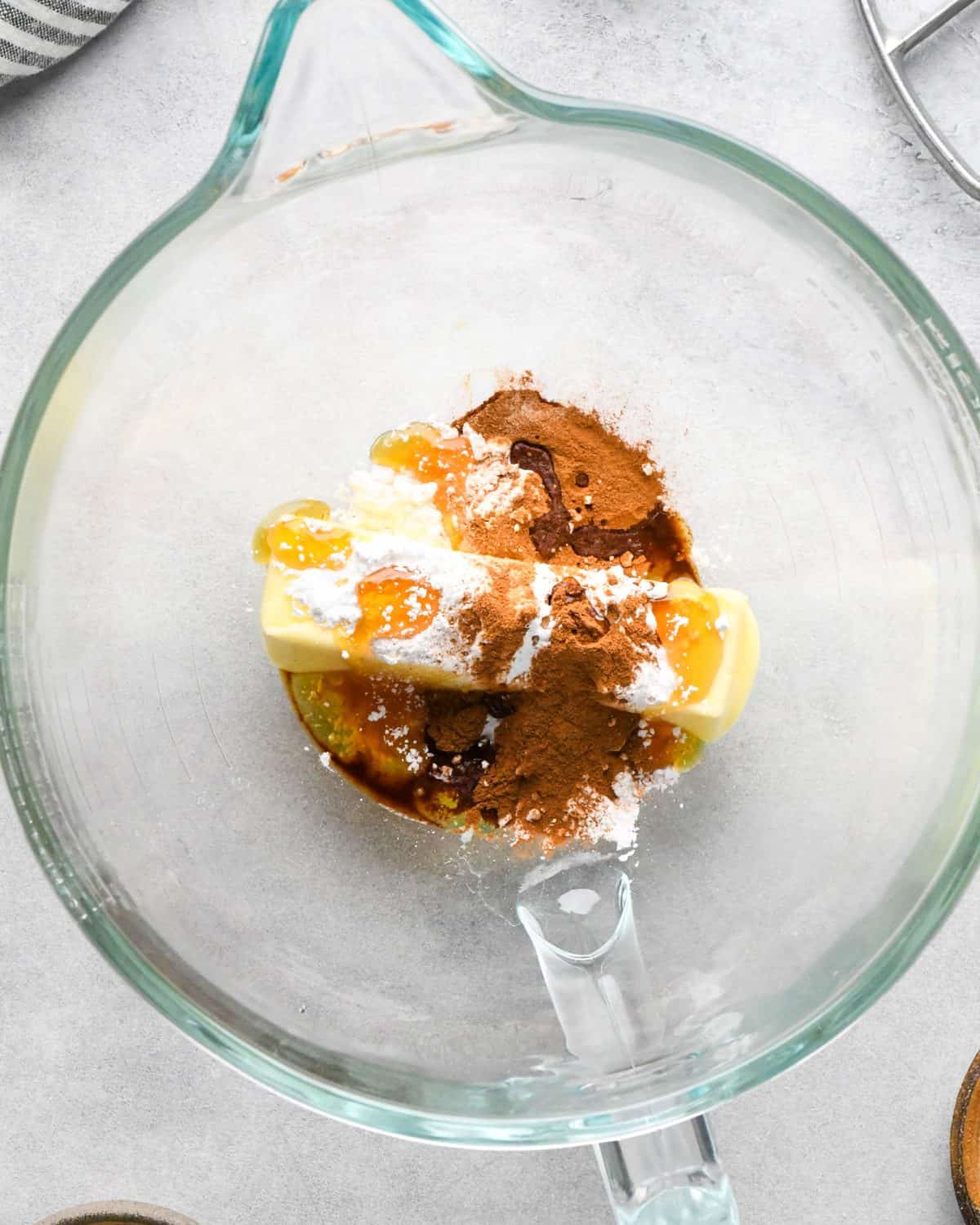 making homemade cinnamon honey butter to serve on top of these pumpkin pancakes - butter, honey, cinnamon, powdered sugar all in a glass mixing bowl before mixing.