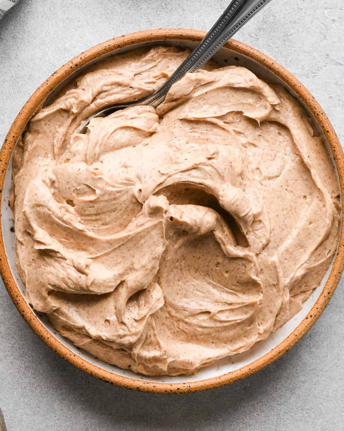 cinnamon honey butter in a ceramic bowl with a metal spoon to be served on top of this pumpkin pancakes recipe