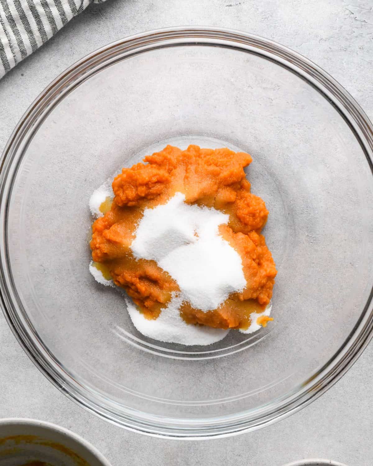 making pumpkin pancakes recipe - pumpkin puree and white sugar in a glass bowl before mixing