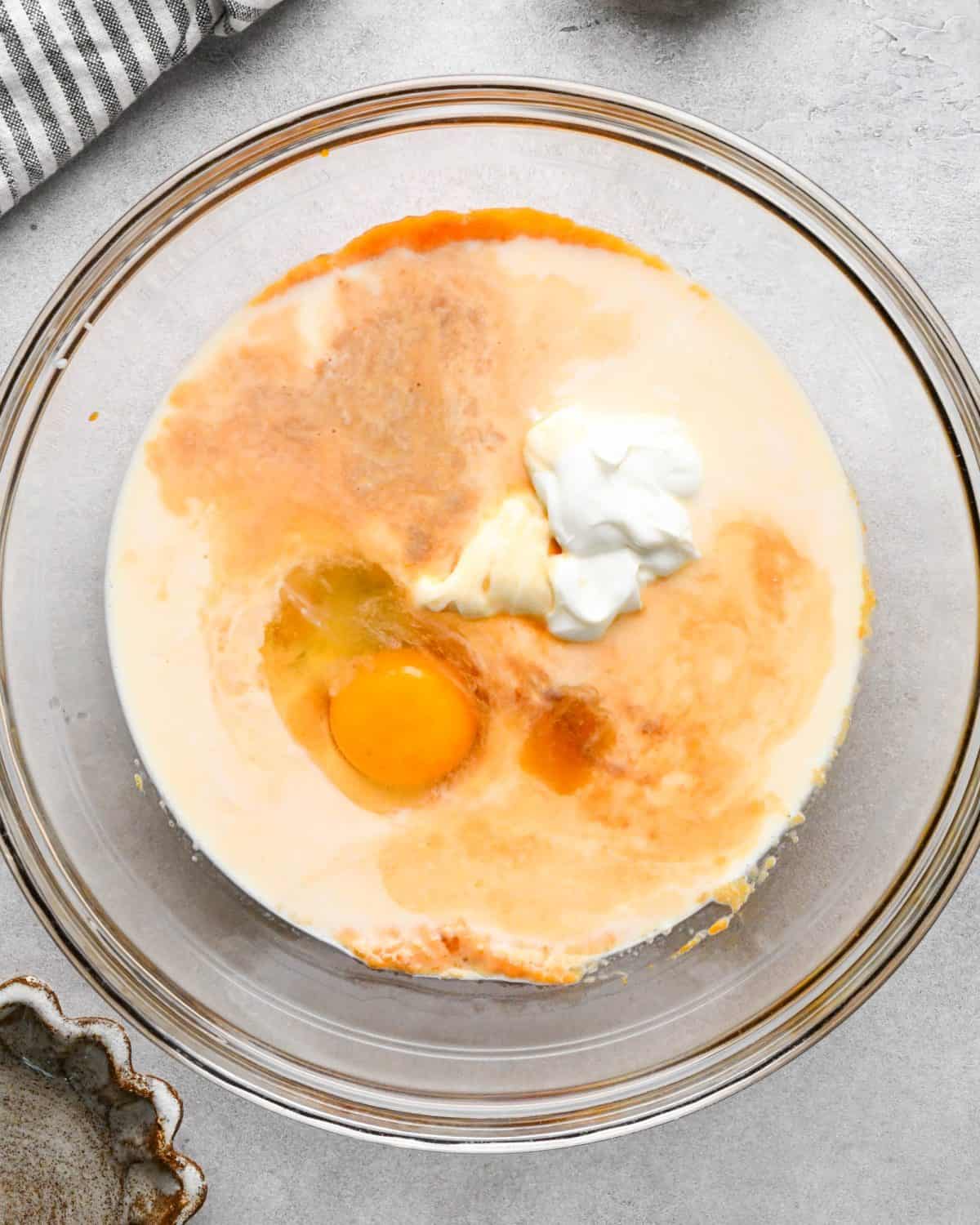 making pumpkin pancakes recipe - egg, milk, greek yogurt, vanilla in a glass bowl before mixing