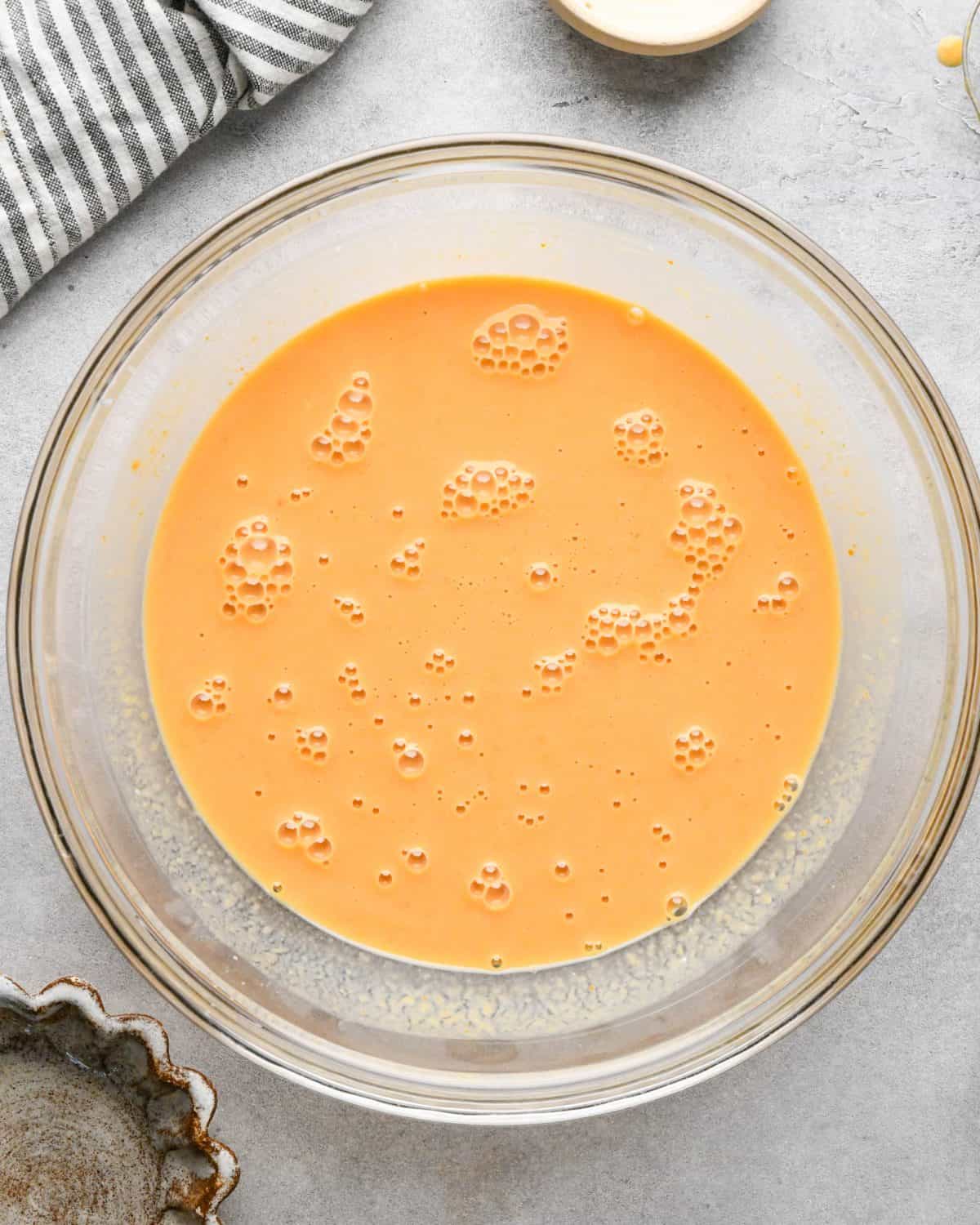 making pumpkin pancakes recipe - wet ingredients in a glass bowl after mixing.