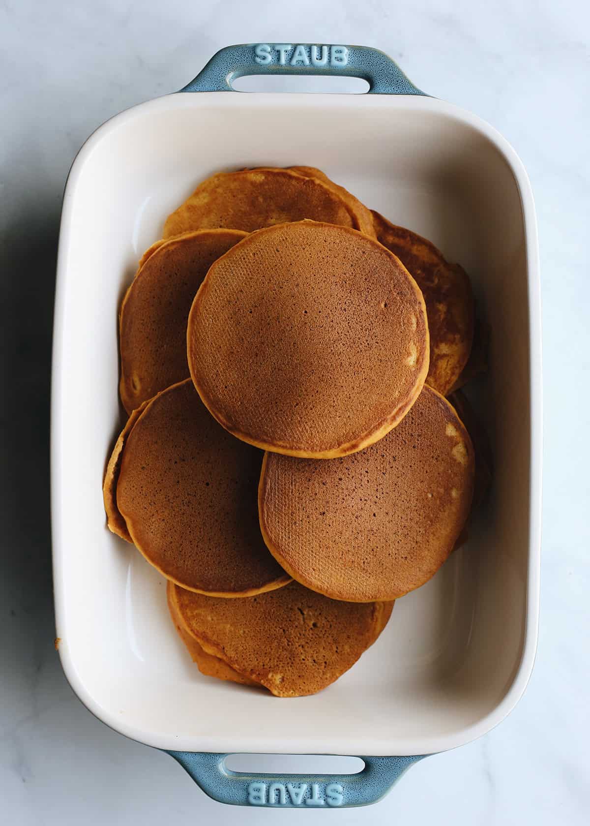 pumpkin pancakes piled in a blue and white rectangular baking dish
