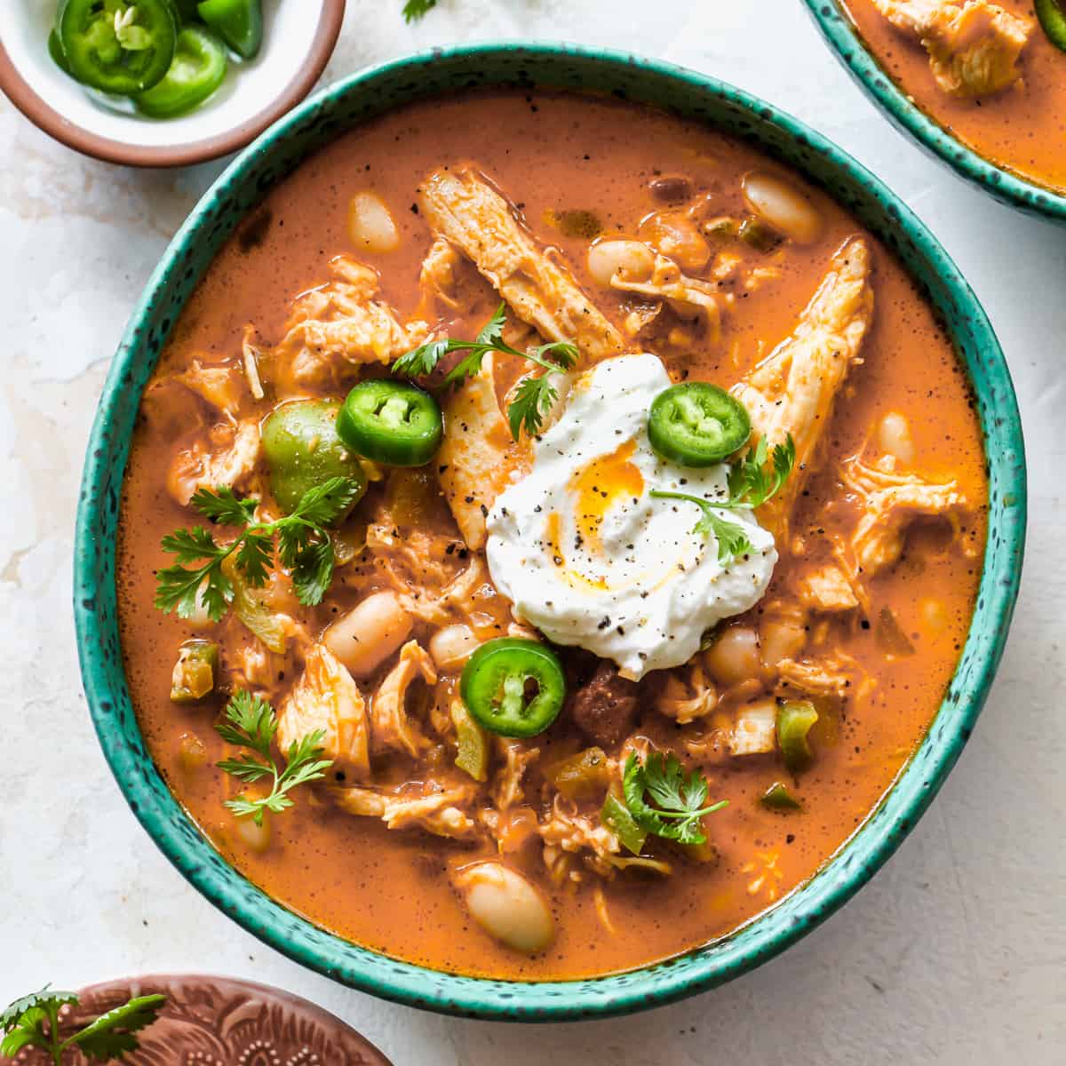 bowl of White Bean Chicken Chili garnished with sour cream, jalapeños, and cilantro