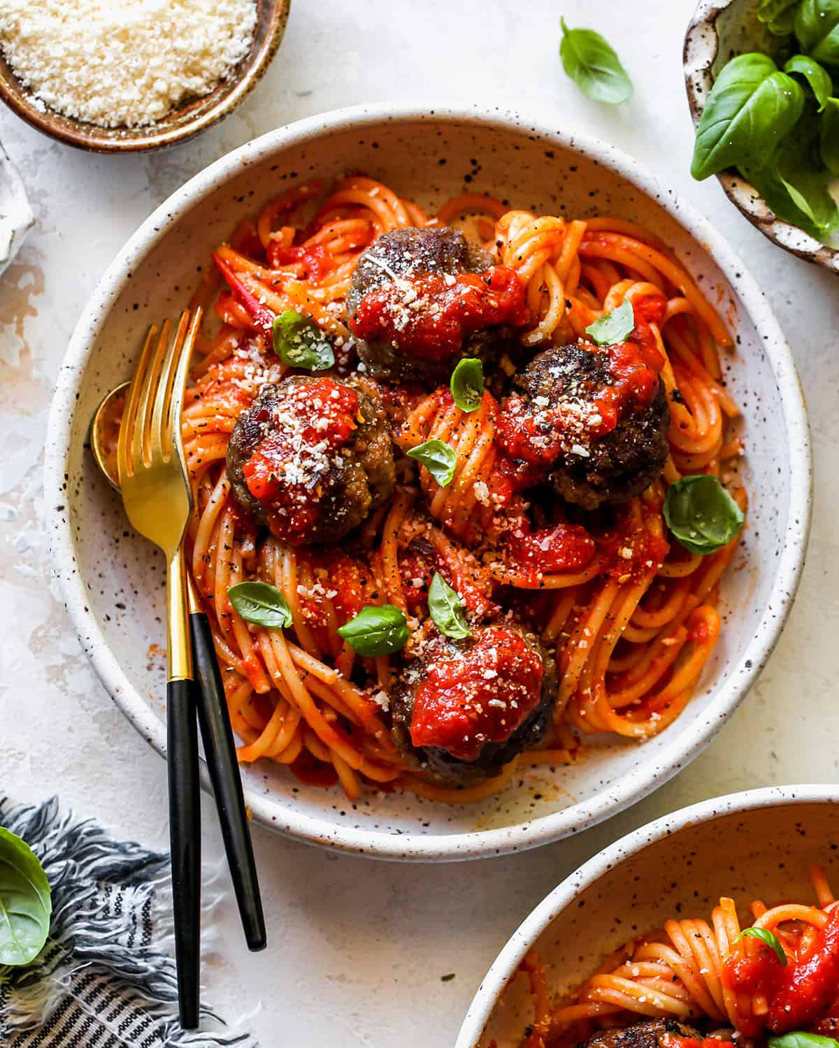 homemade meatballs over pasta in marinara sauce garnished with basil