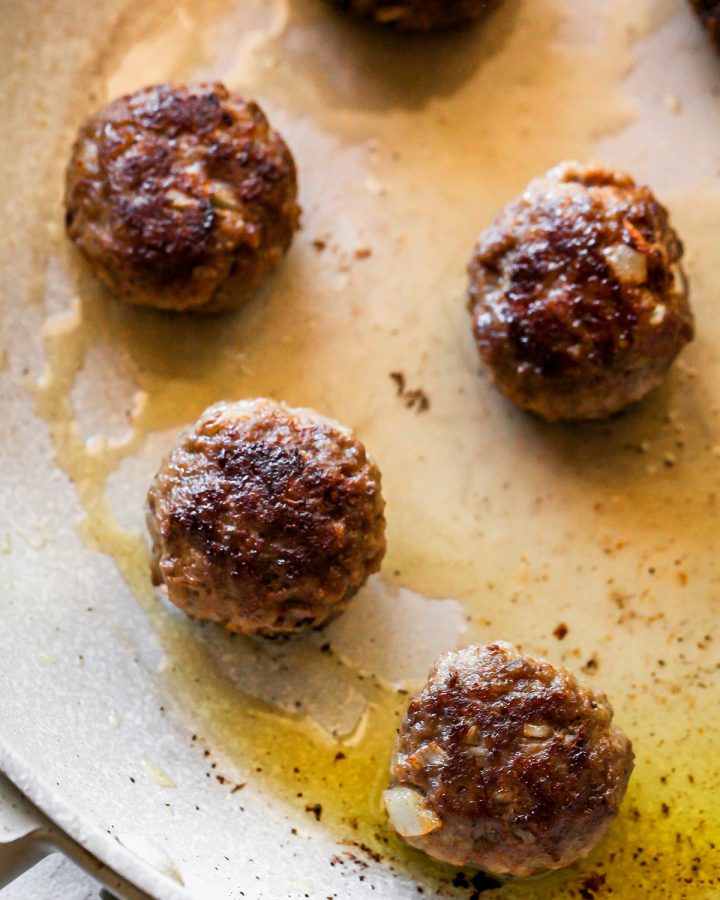 5 homemade meatballs cooked in olive oil in a pan