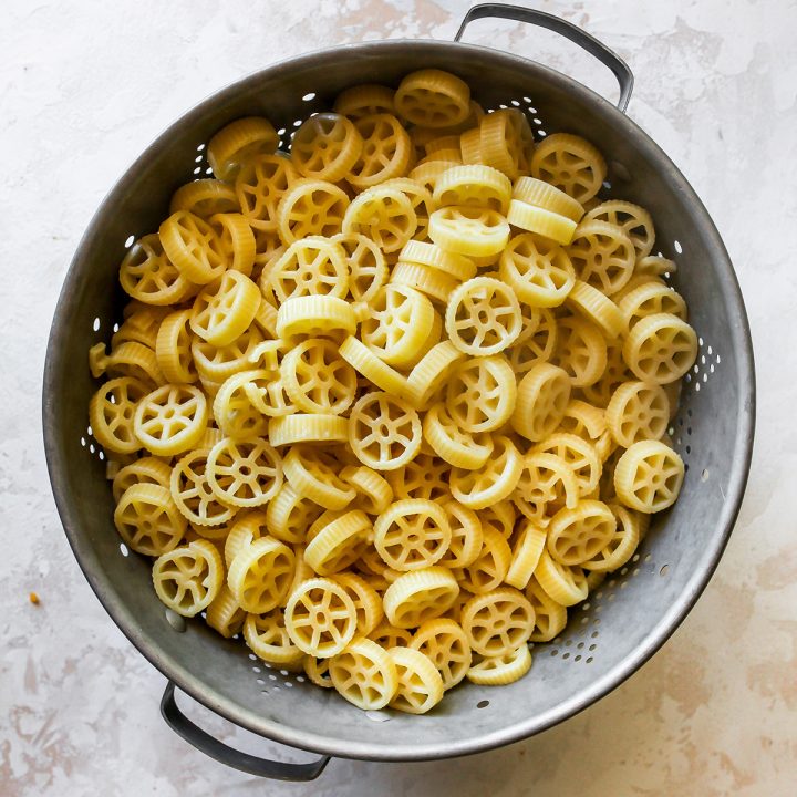 cooked wagon wheel pasta in a strainer to be used in this Butternut Squash Mac and Cheese recipe
