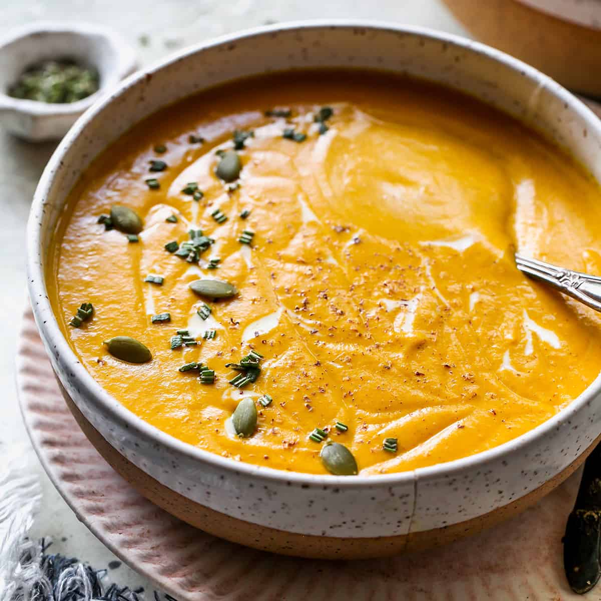 a bowl of Sweet Potato Soup garnished with rosemary, cream and seeds. 