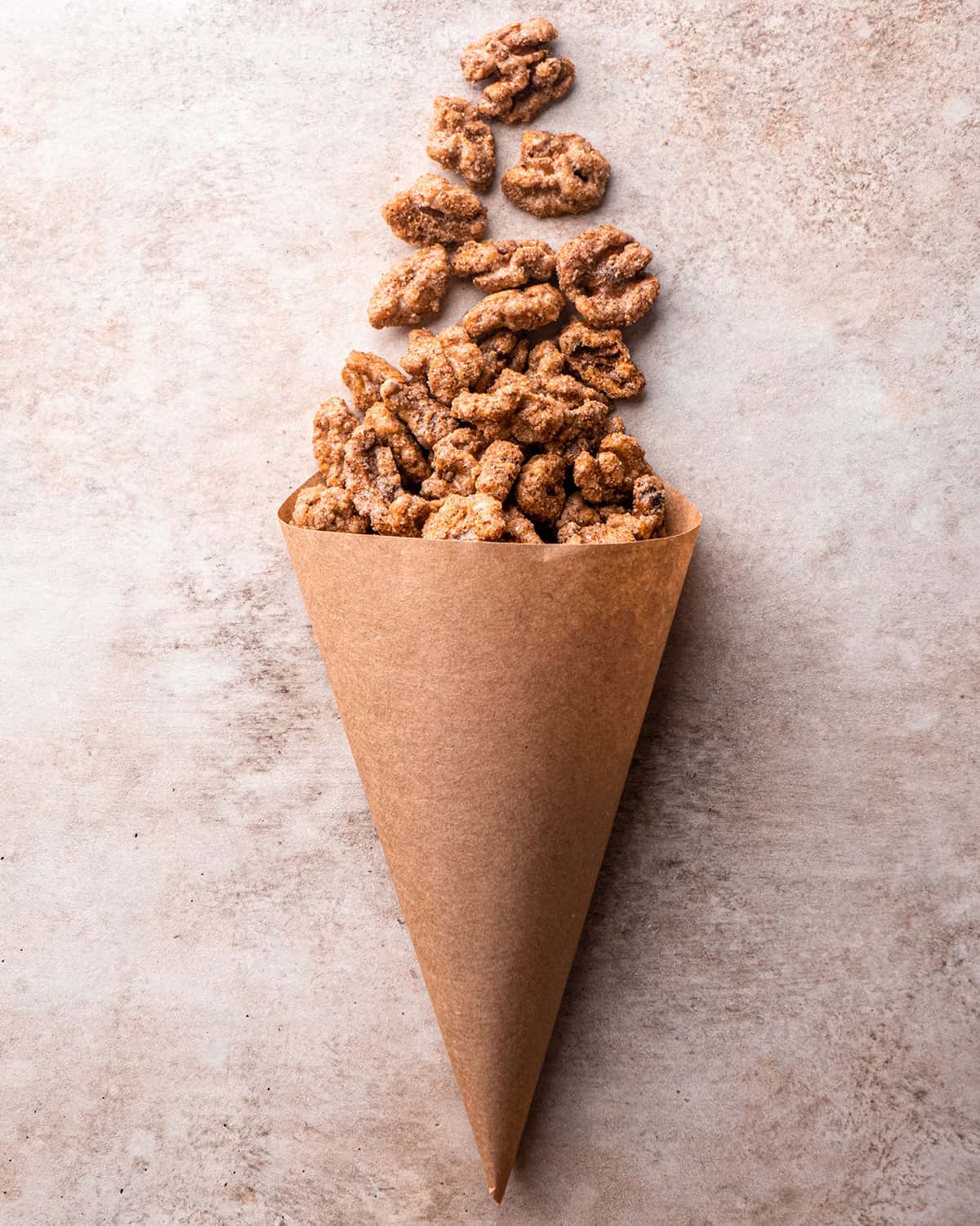 Candied Walnuts spilling out of a brown paper cone 