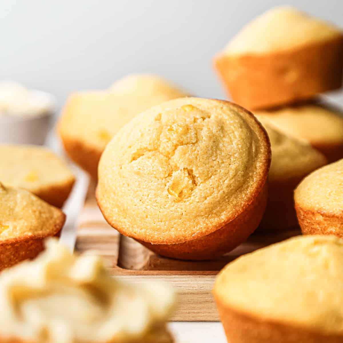 front view of Cornbread Muffins stacked on a wooden cutting board