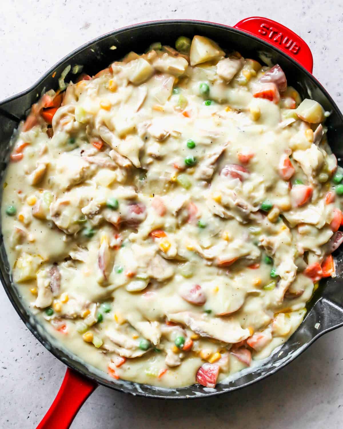 turkey pot pie filling in a red cast iron skillet.