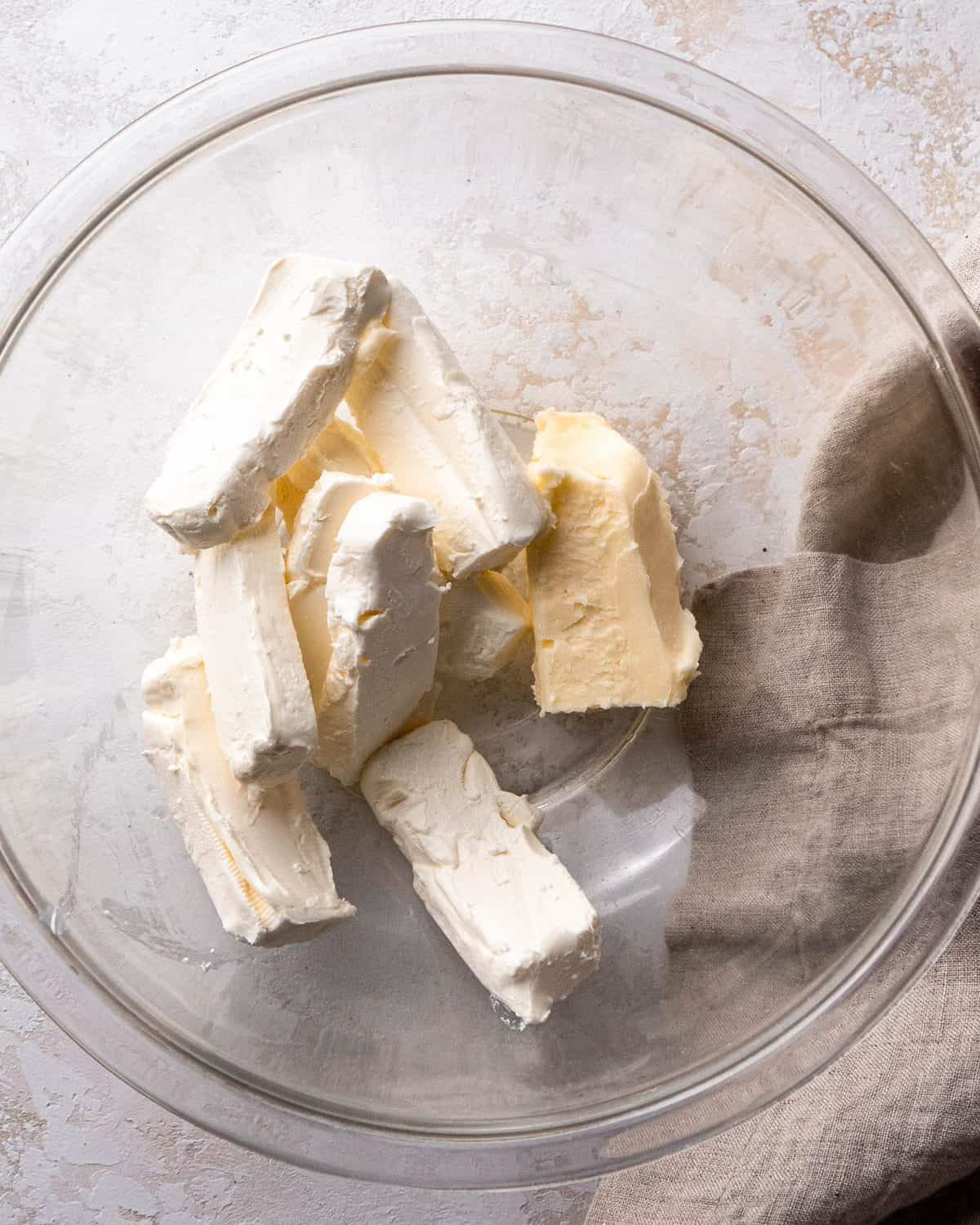 making Oreo pie recipe - softened cream cheese and butter in a glass bowl on a gray surface before mixing