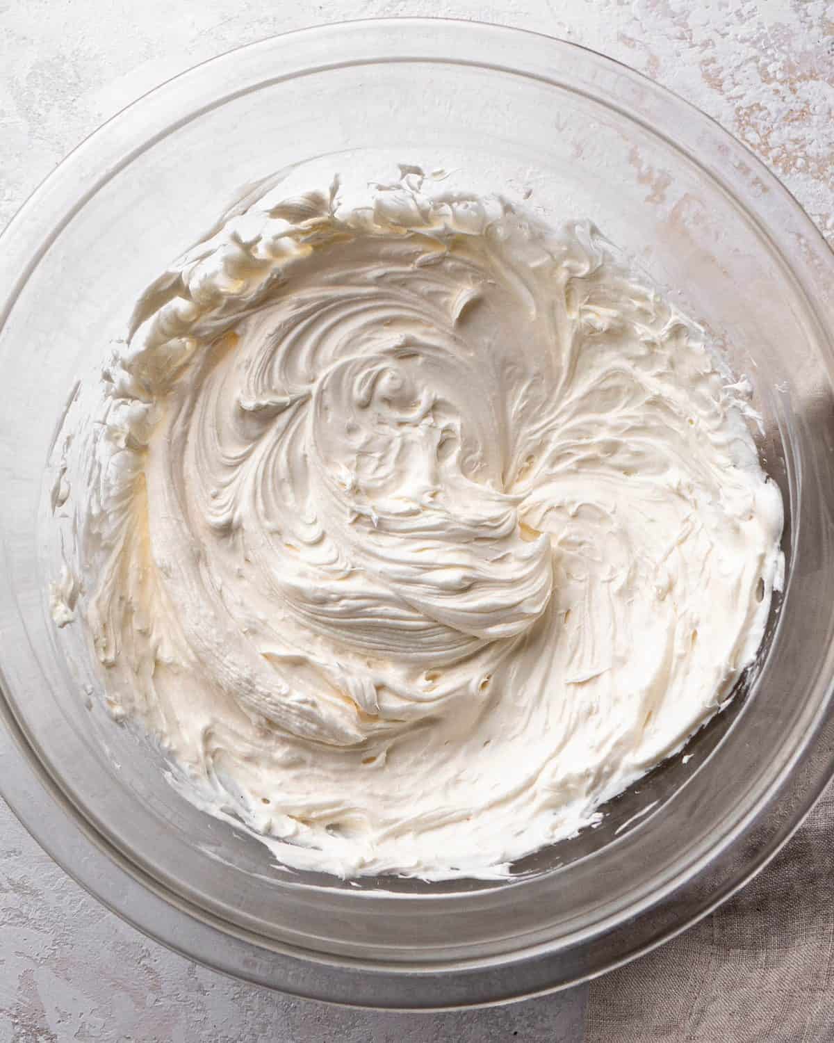 making Oreo pie recipe - softened butter and cream cheese after being beaten together in a glass mixing bowl on a gray surface