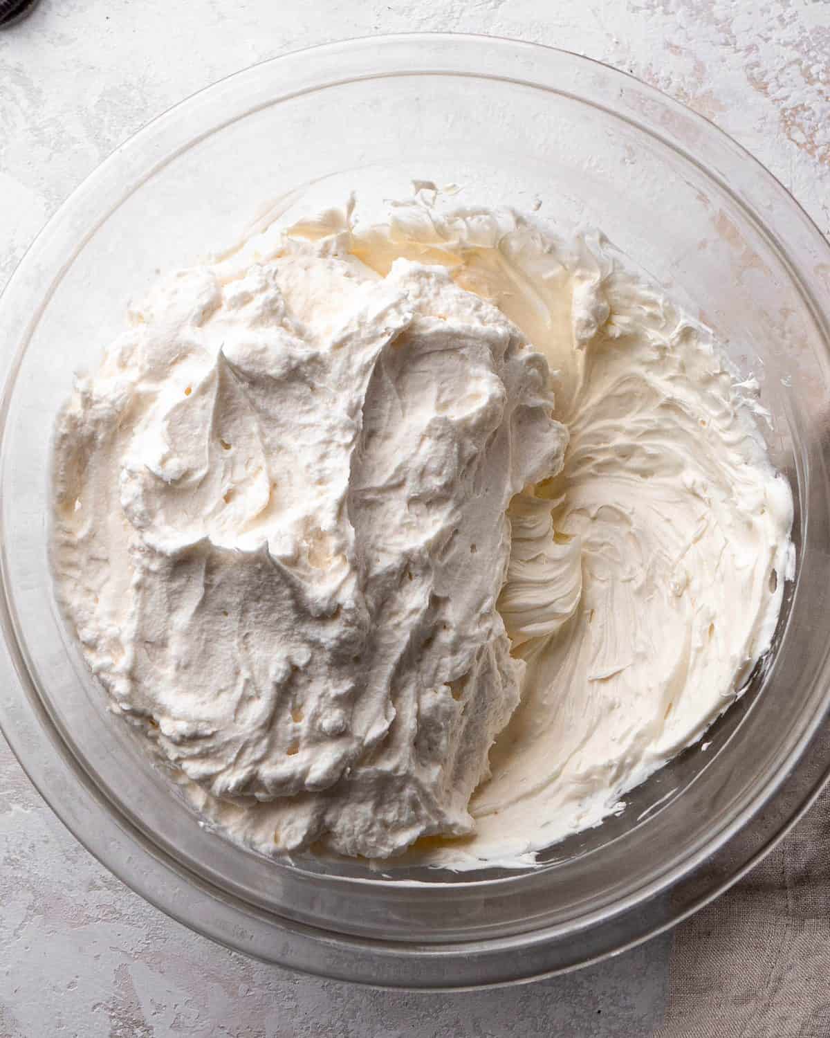 making Oreo pie recipe - Whipped cream added to the cream cheese and butter mixture in a glass bowl before mixing