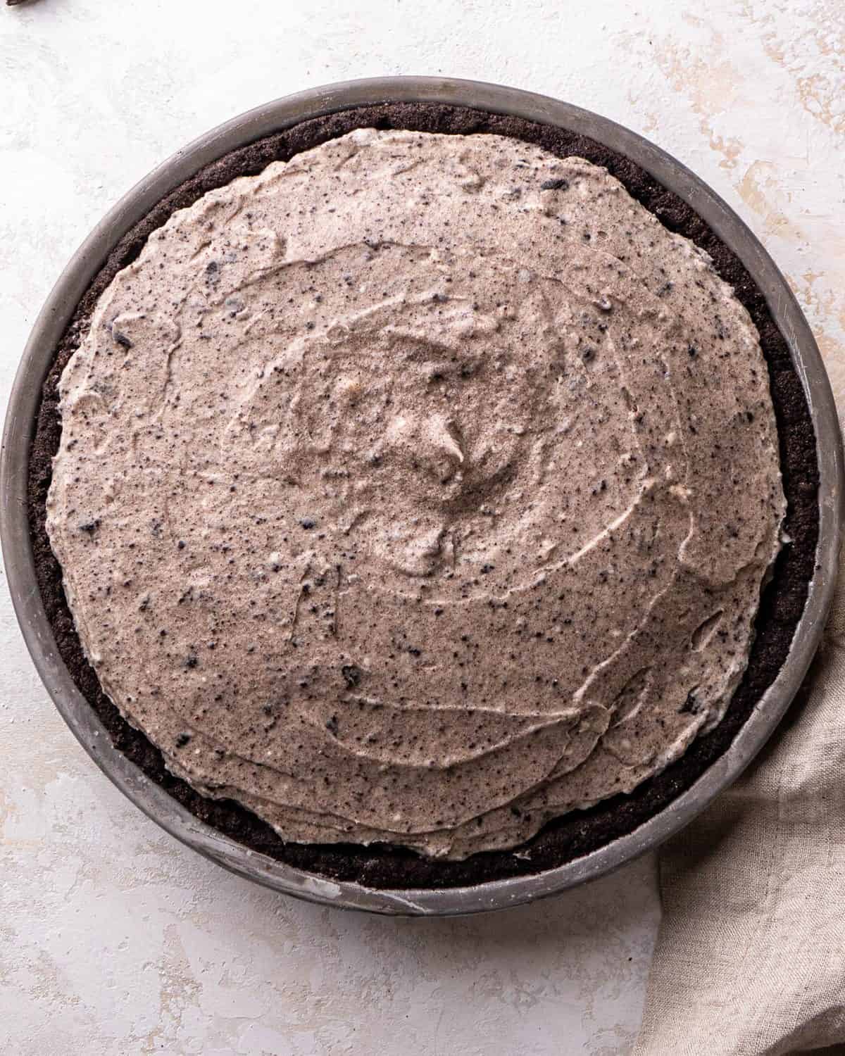 making Oreo pie recipe - filling spread into the Oreo crust in a gray pie dish