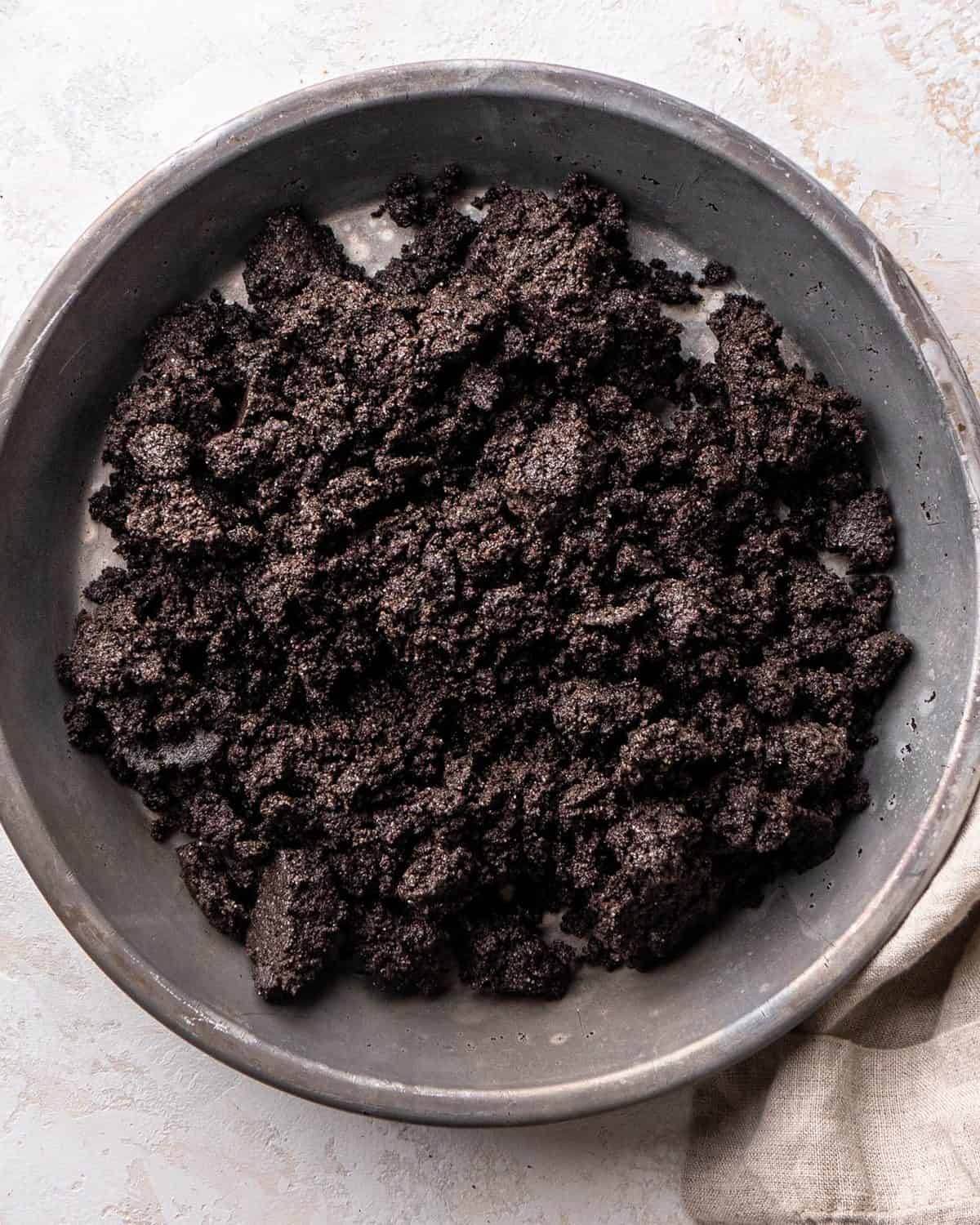 making oreo pie recipe - Oreo crust mixture in a metal pie dish before spreading around