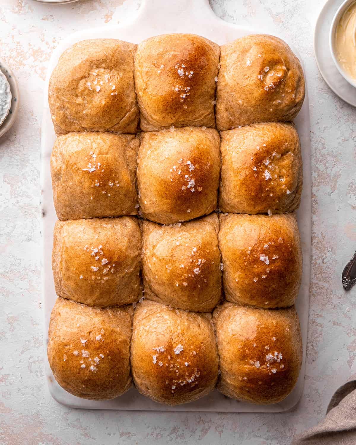 overhead view of 12 Whole Wheat Rolls with melted butter and sea salt on top after baking