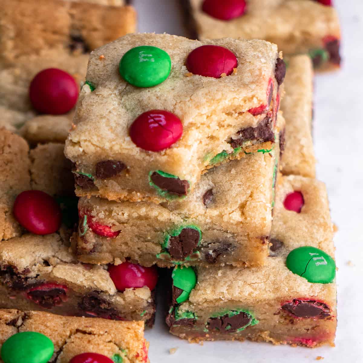 a stack of two M&M Christams Cookie Bars on top of other bars, the top one has a bite taken out of it