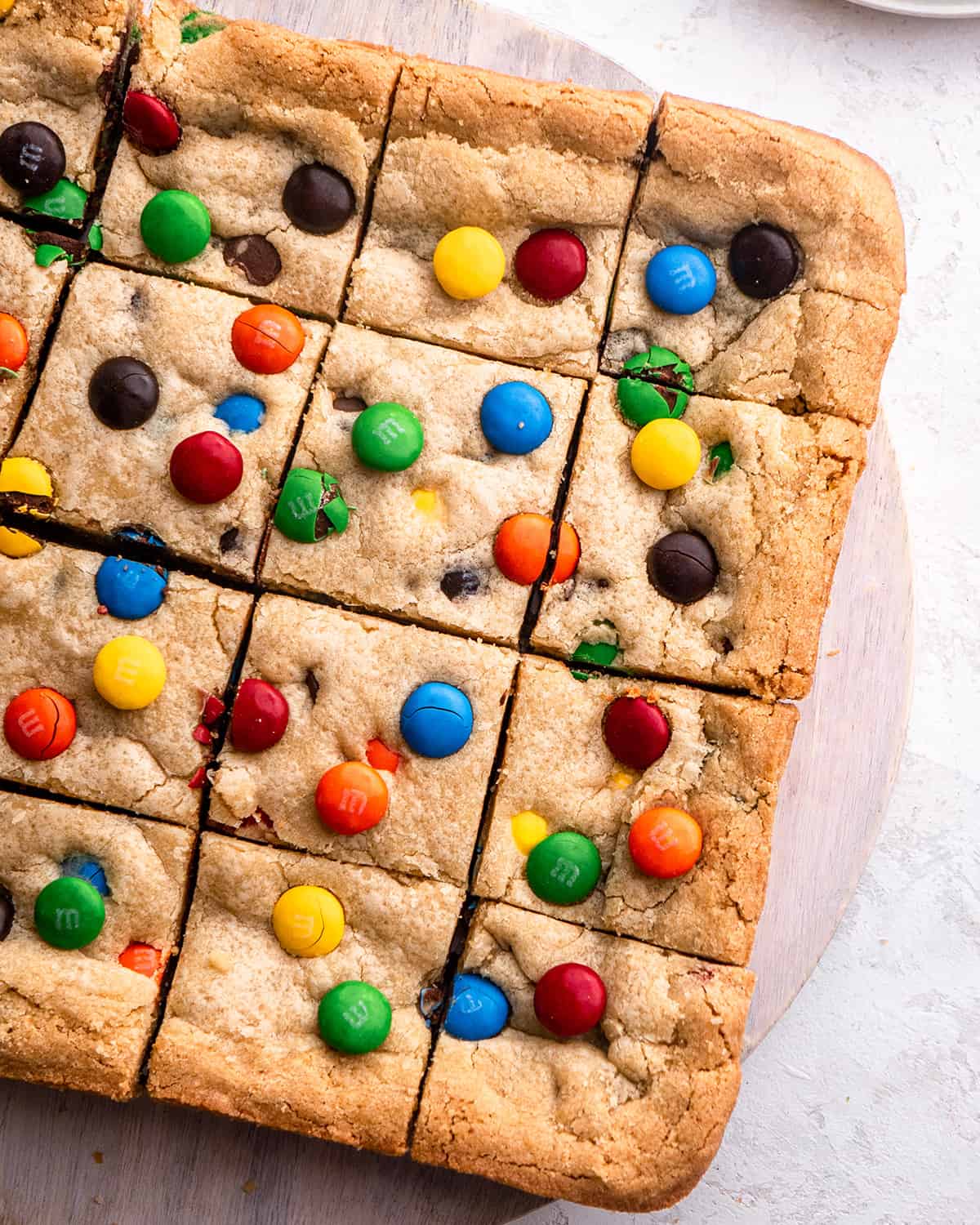 M&M Cookie Bars cut into 16 squares on a round serving platter