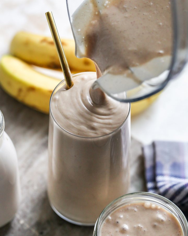 Banana Peanut Butter Smoothie being poured from the blending container into a glass