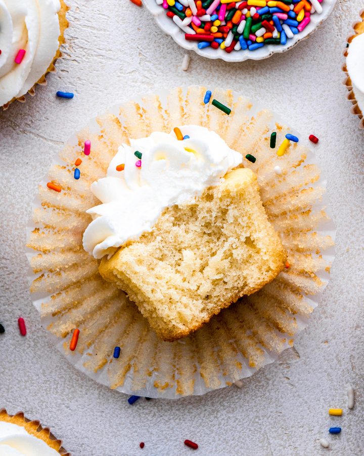 a Vanilla Cupcake laying on it's side with a bite taken out of it 