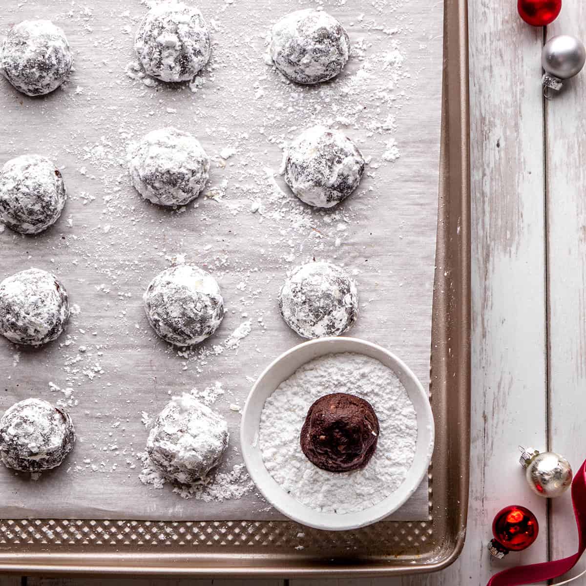 two photos showing How to Make Chocolate Snowball Cookies - rolling baked cookies in powdered sugar