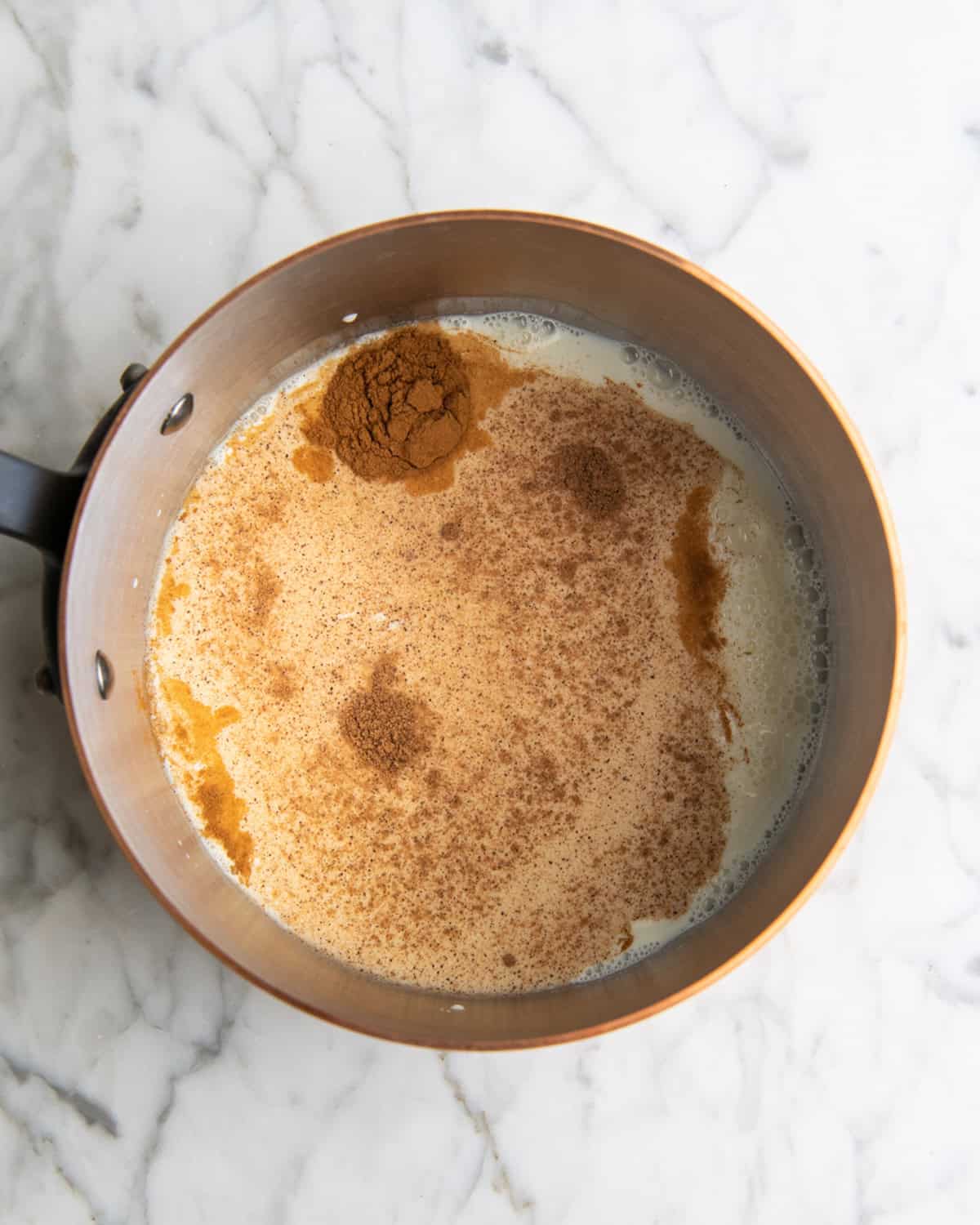 how to make eggnog recipe cinnamon and nutmeg added to milk in a copper saucepan before mixing