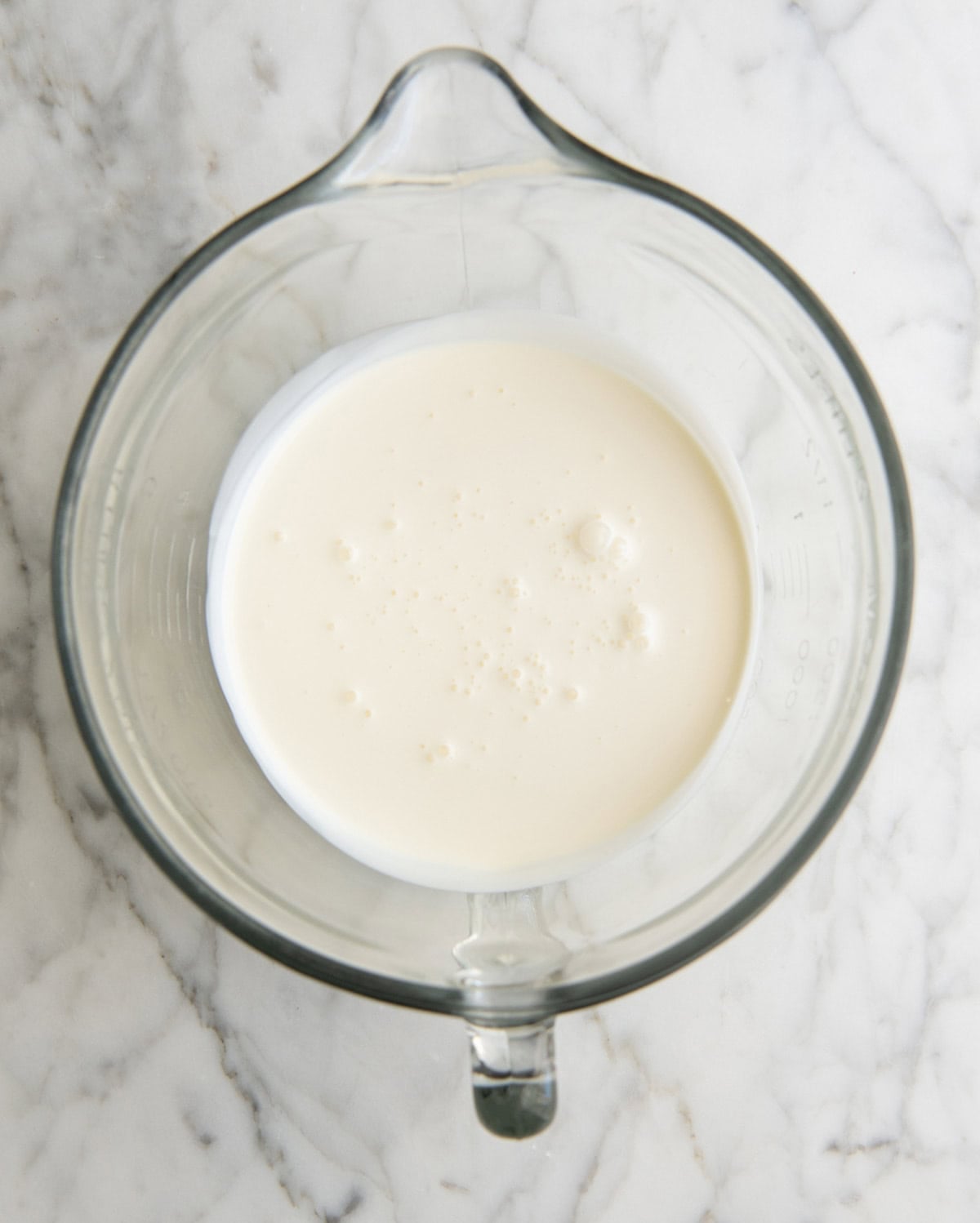 how to make eggnog recipe - heavy cream in a glass batter bowl in a marble surface