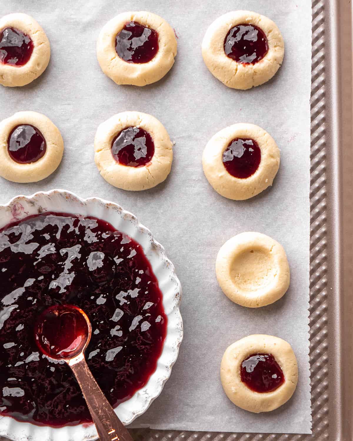 two photos showing how to make Thumbprint Cookies - filling cookies with raspberry jam before baking
