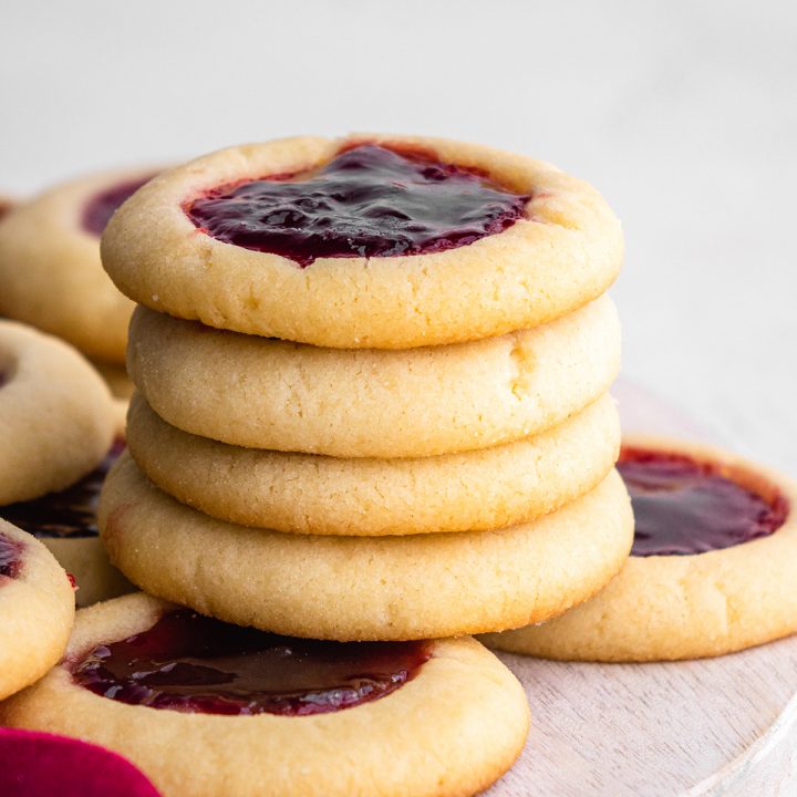 stack of four Thumbprint Cookies on top of other raspberry thumbprint cookies
