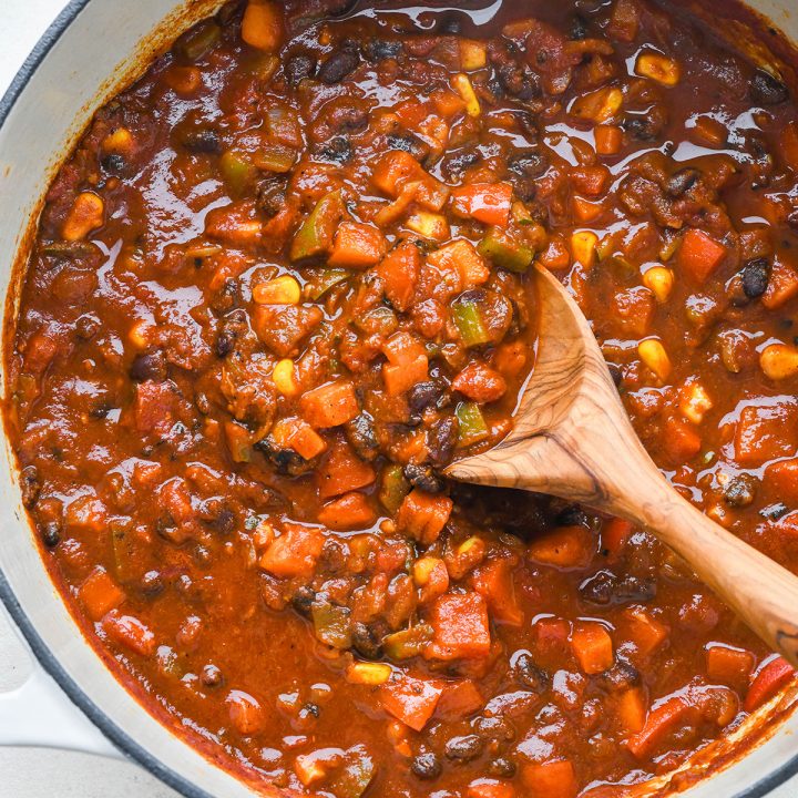 Vegetarian Chili in a pot with a wooden spoon taking a scoop