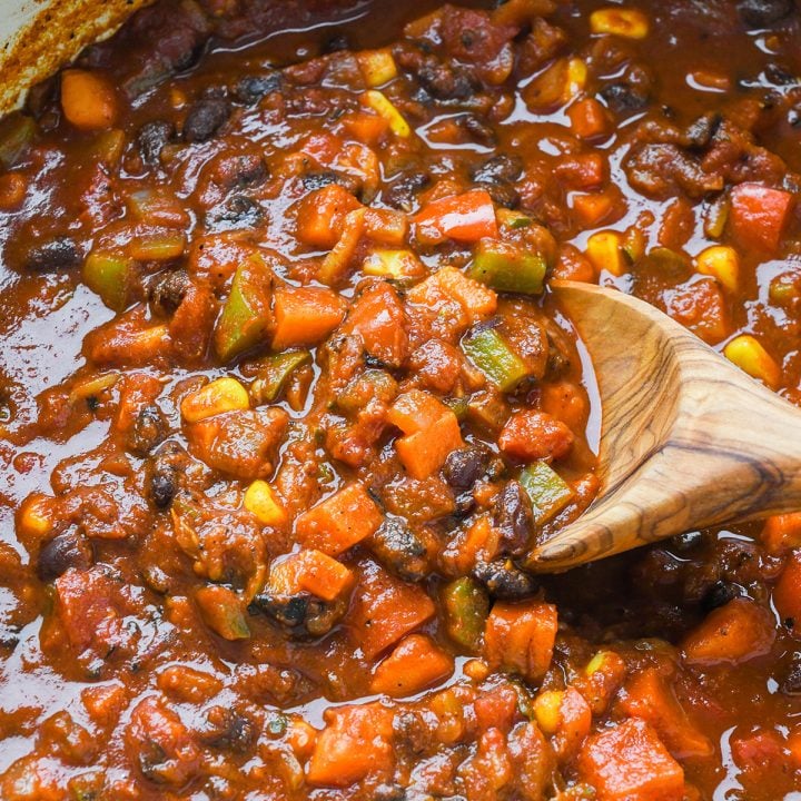 Vegetarian Chili in a pot with a wooden spoon taking a scoop