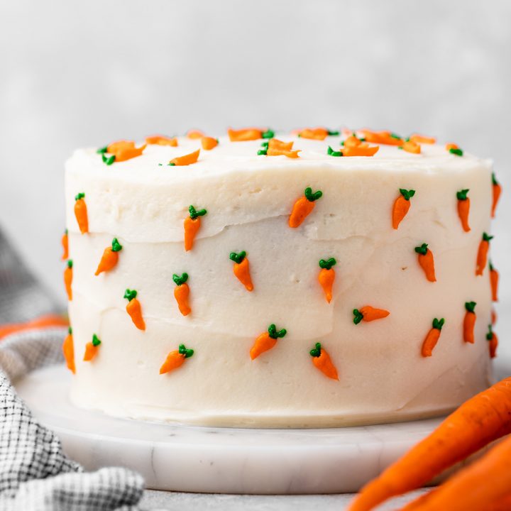 a whole carrot cake with cream cheese frosting and tiny frosting carrots all around it