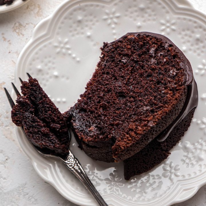 a piece of Chocolate Bundt Cake on a plate with a fork that has taken a bite out of it