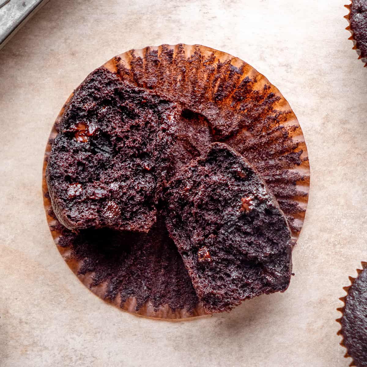 a Chocolate Banana Muffin cut in half laying o na muffin liner so the center is visible