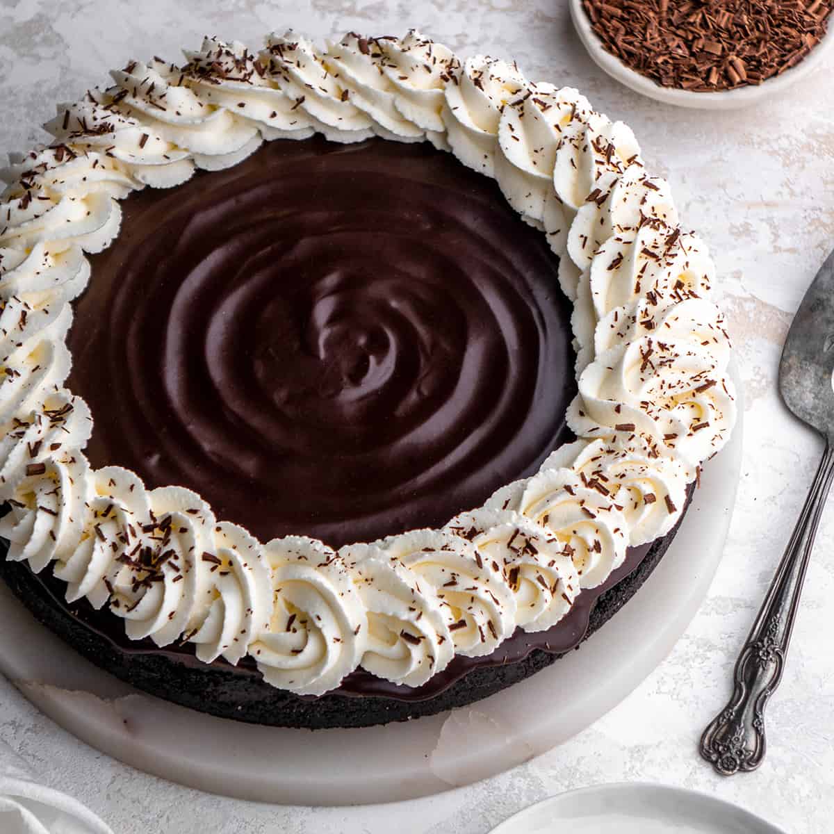 Chocolate Cheesecake on a plate topped with whipped cream and chocolate shavings 