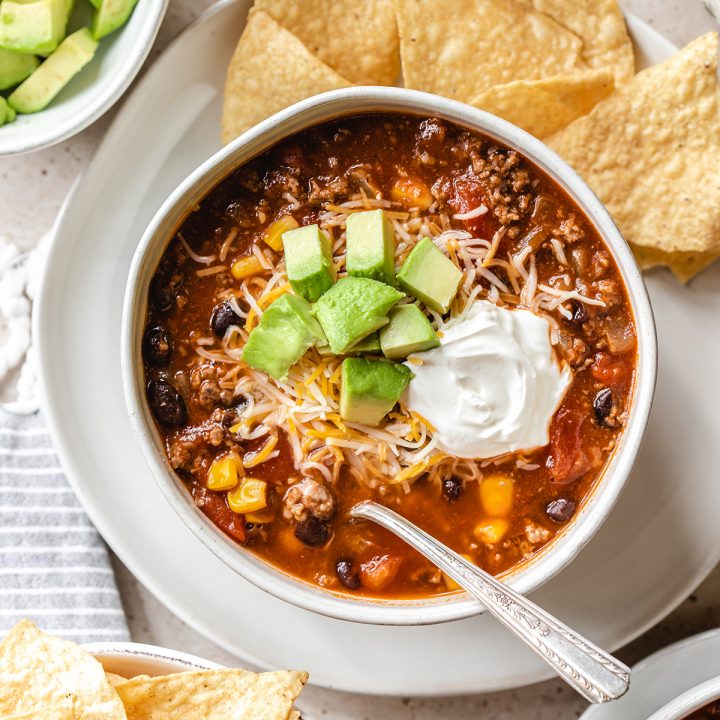 a bowl of Taco Soup topped with sour cream, cheese and avocados