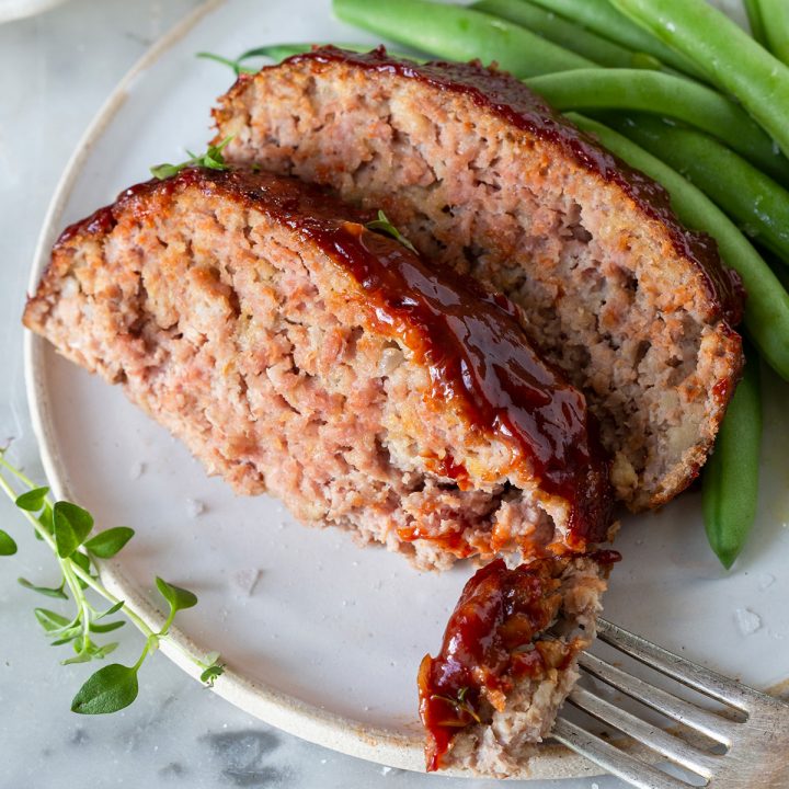two slices of Turkey Meatloaf on a plate with green beans and a fork