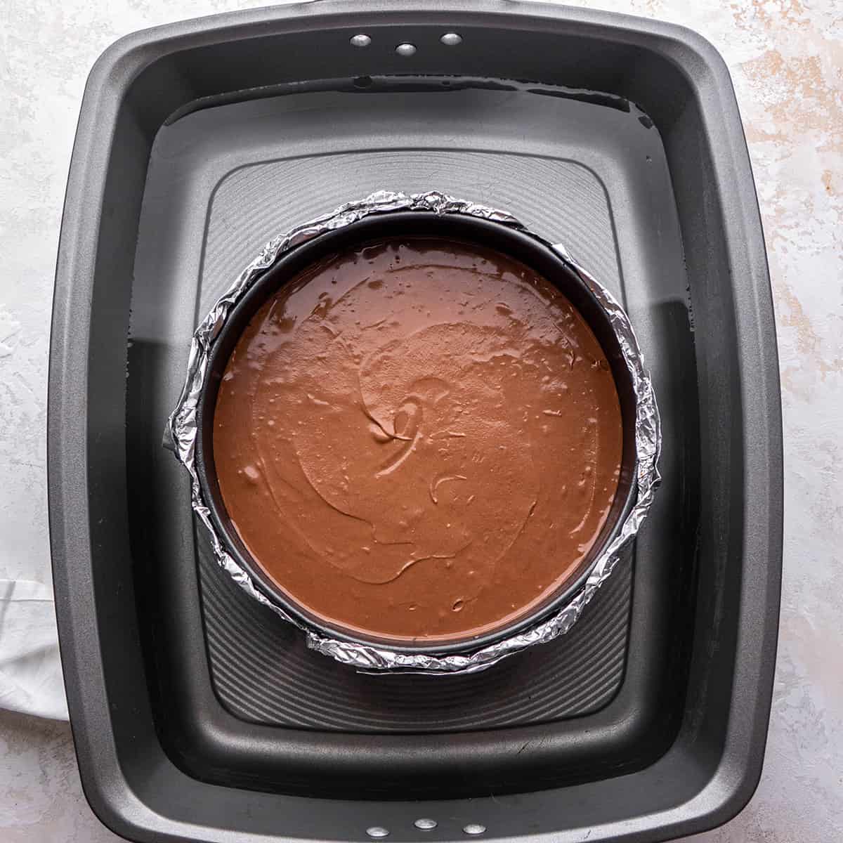 photo of chocolate cheesecake in a water bath before baking