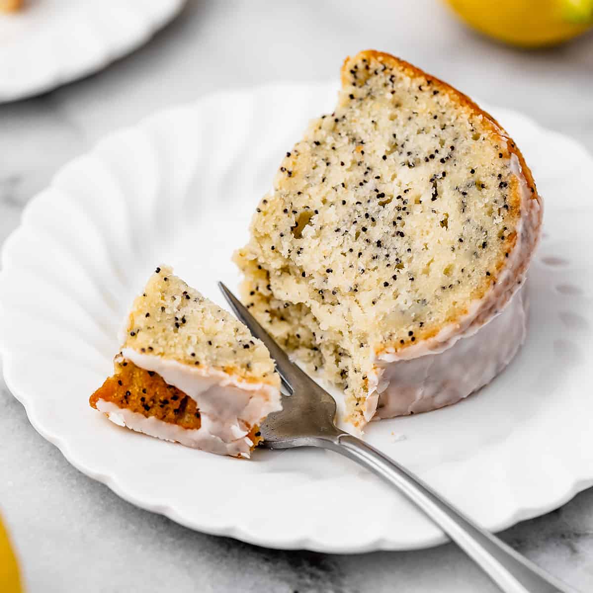 a fork taking a bite of Lemon Poppy Seed Cake on a plate