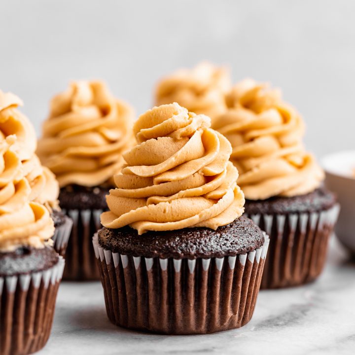 Peanut Butter Frosting piped on top of chocolate cupcakes