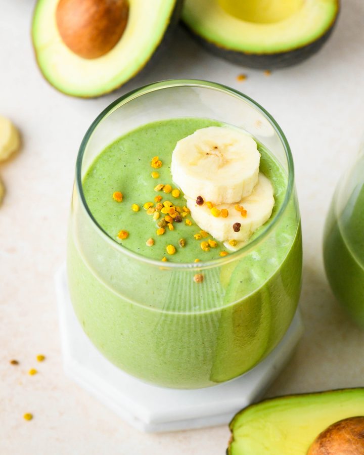 banana Avocado Smoothie in a glass topped with sliced bananas and bee pollen