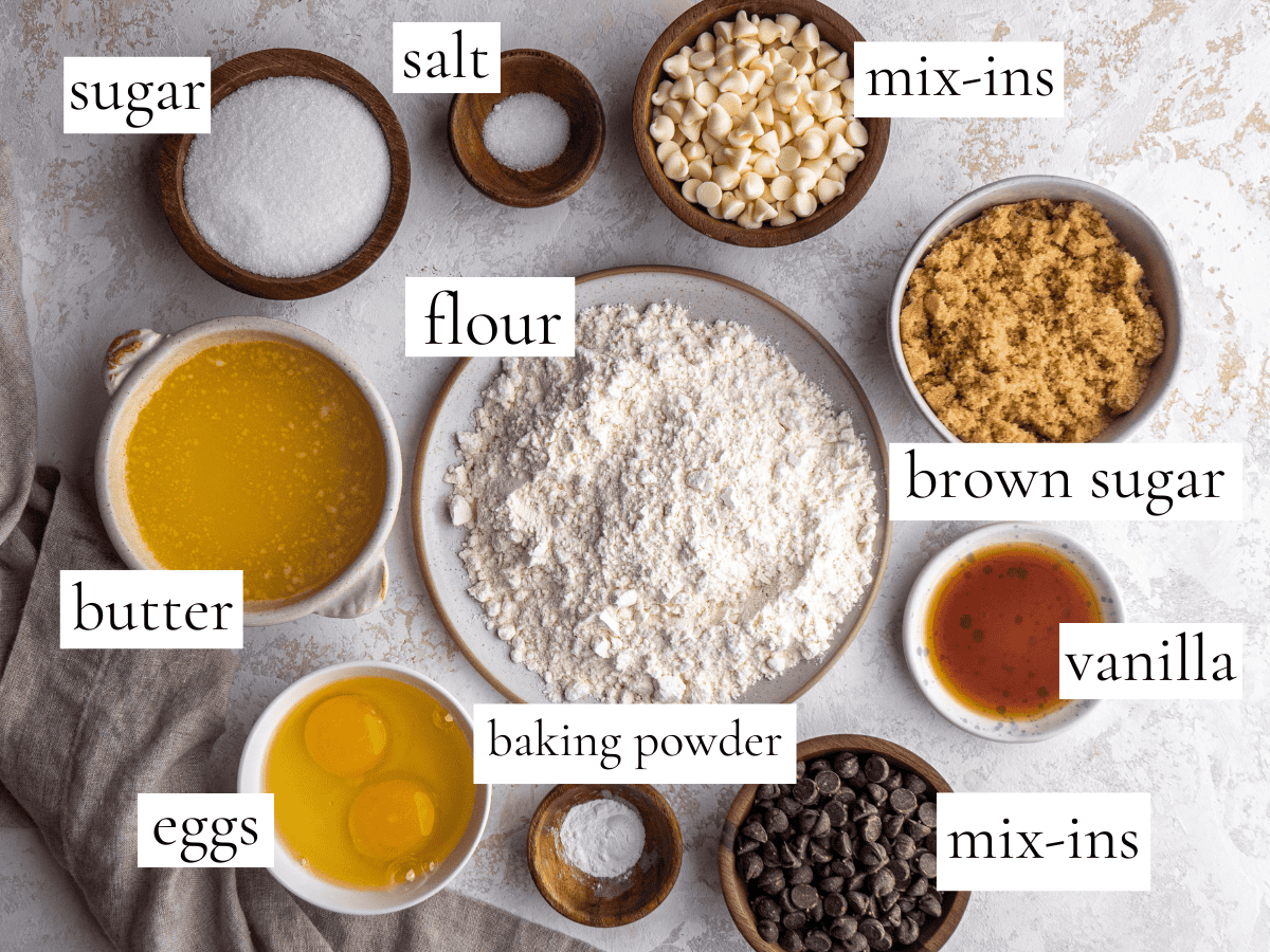 overhead photo of the ingredients in this blondies recipe all in bowls and labeled, the ingredients are flour, sugar, butter, brown sugar, salt, baking powder, vanilla and mix-ins.