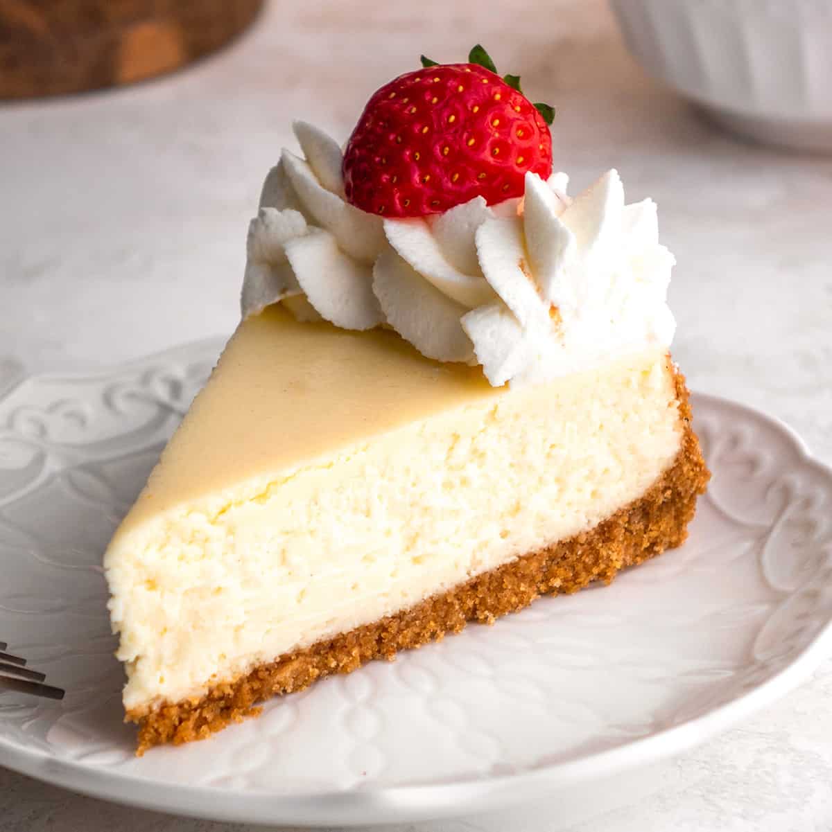 a slice of cheesecake on a plate topped with whipped cream and a strawberry