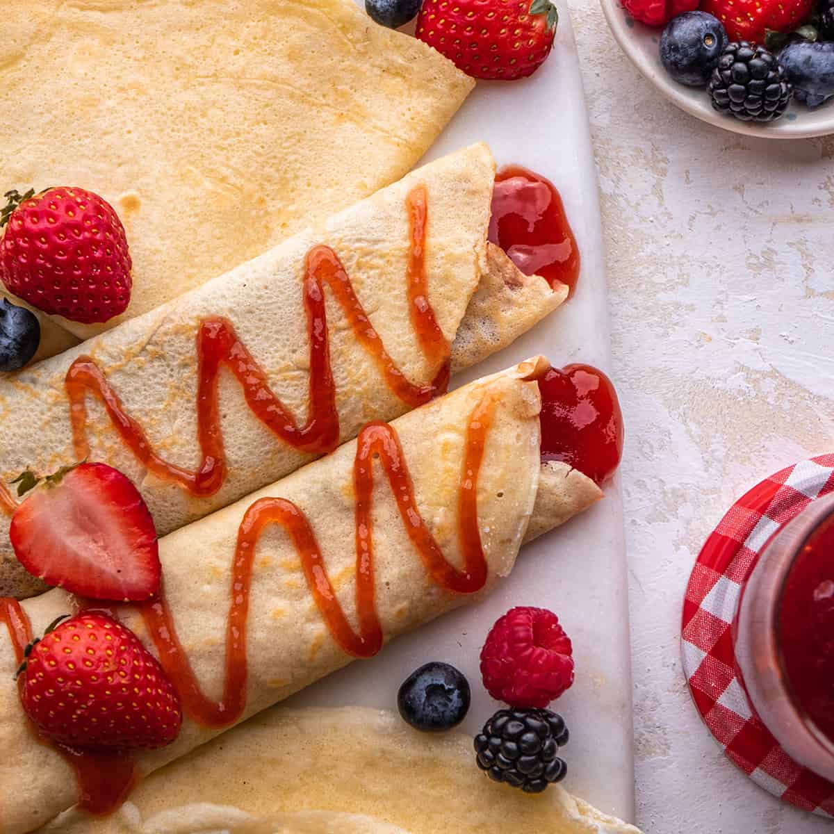 two crepes filled and drizzled with strawberry jam